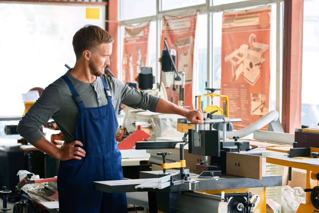 Young Workman Inspecting Machines in Shop