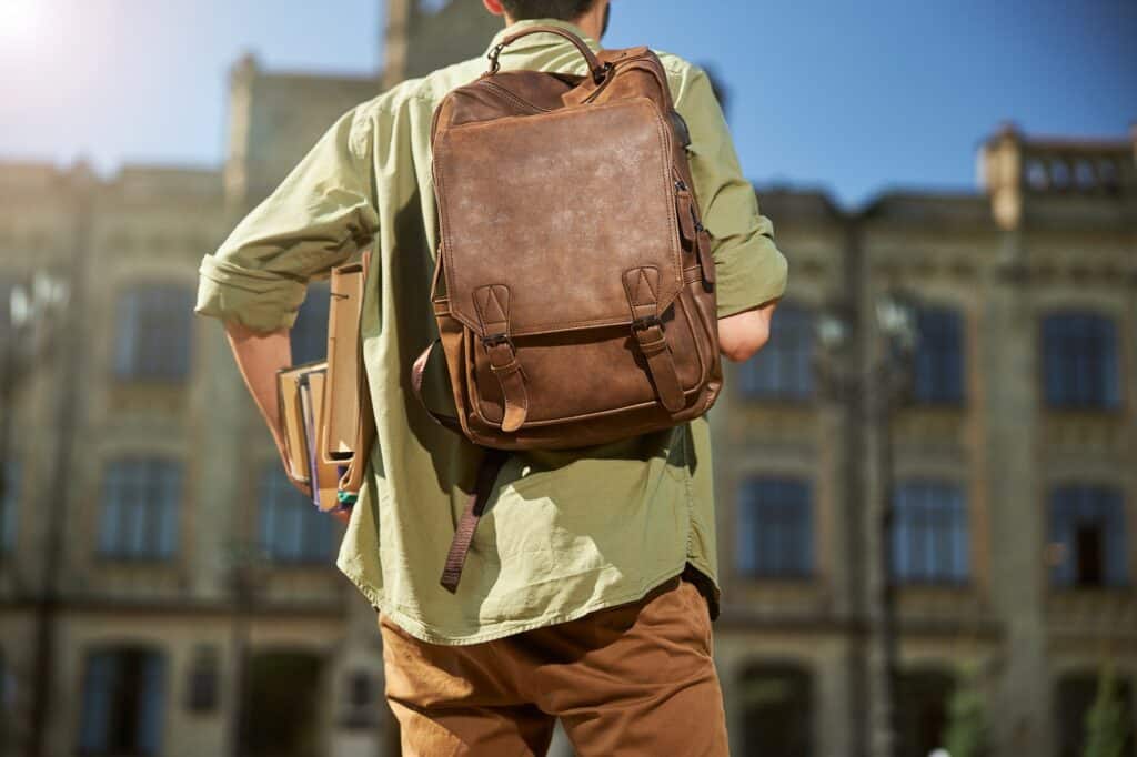 Dark-haired man walking towards a university building
